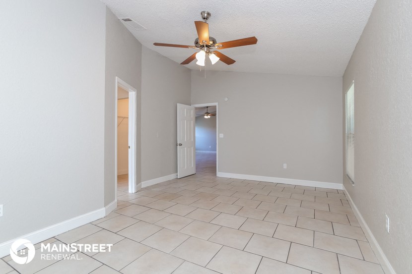 an empty living room with a ceiling fan and tiled floor