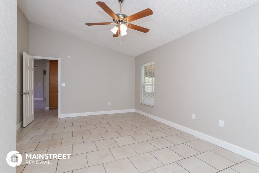 the spacious living room with tile flooring and a ceiling fan