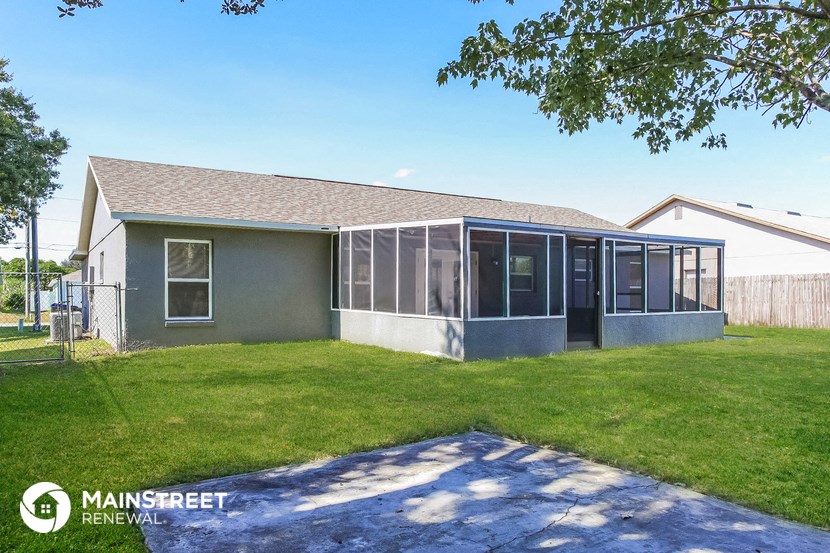 a small gray house with a lawn and a patio