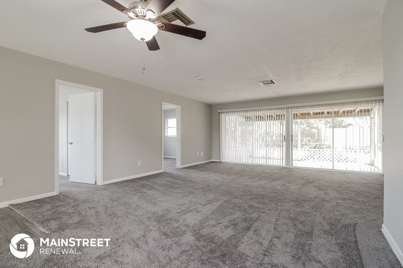 an empty living room with a ceiling fan and a window