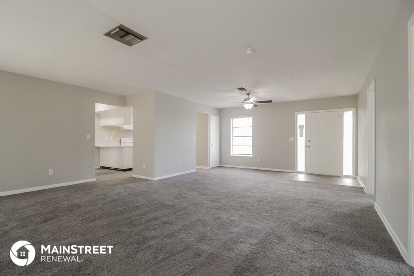 an empty living room with carpet and a ceiling fan