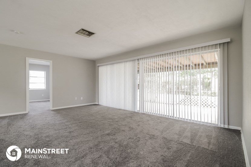an empty living room with sliding glass doors to a patio