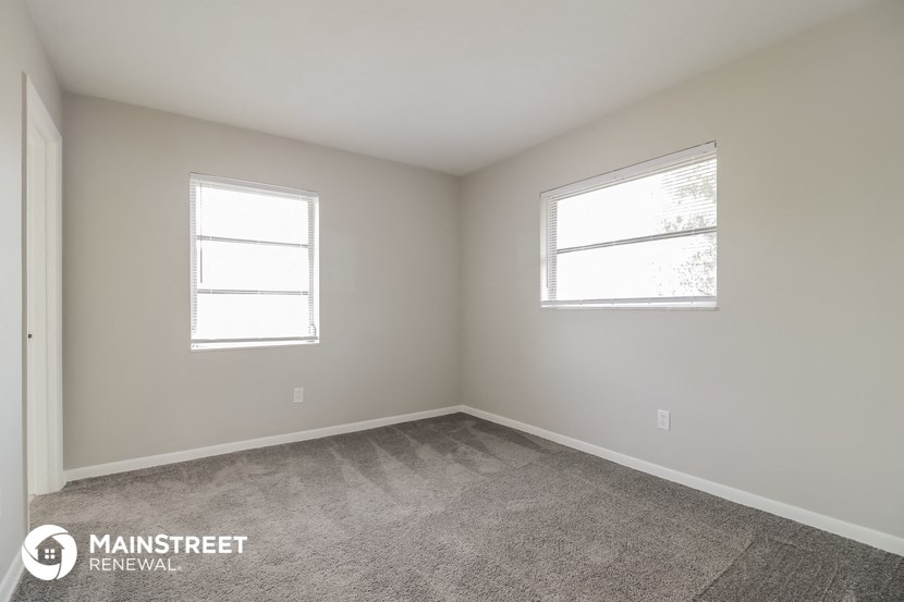 a bedroom with two windows and a carpeted floor