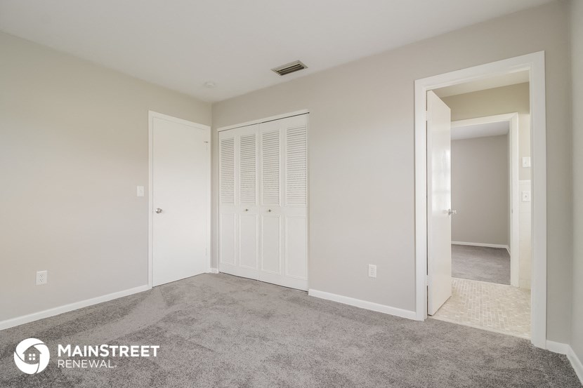 a bedroom with a carpeted floor and a door to a closet