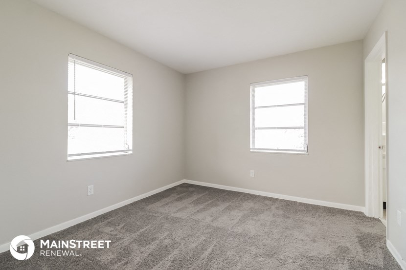 the upstairs bedroom with carpet and two windows