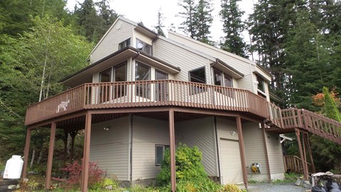 A house with a balcony and a deck in the woods.