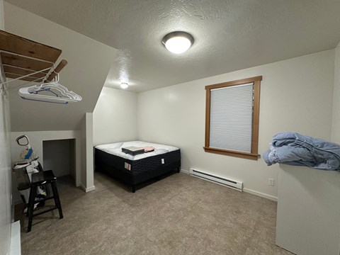 A bedroom with a bed, a chair, and a window.