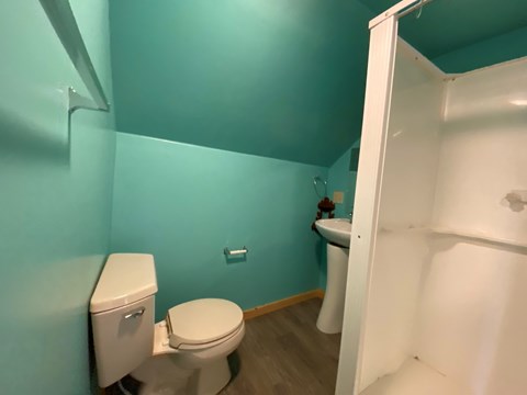 A white toilet sits in a bathroom with a blue wall.