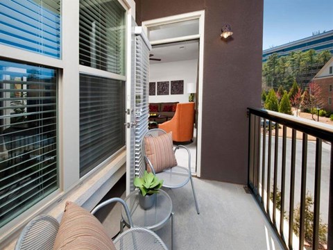 a balcony with chairs and a table and a door to a living room