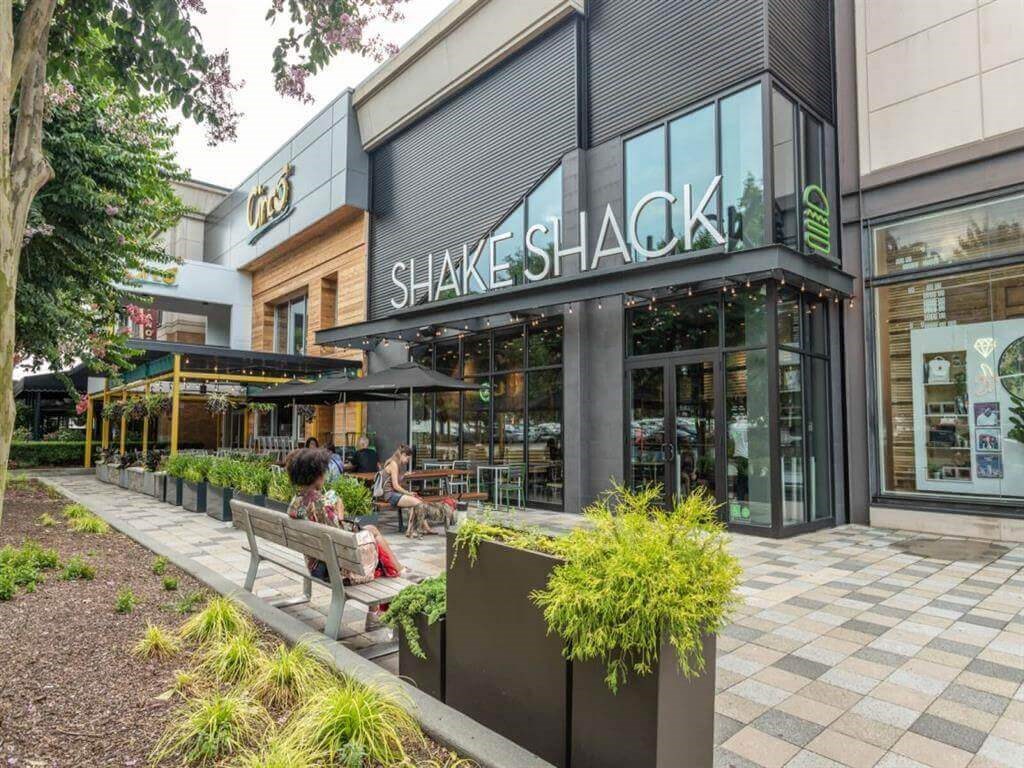 a store front of shake shack with people sitting on benches