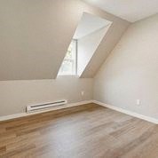an empty bedroom with a window and wooden floors