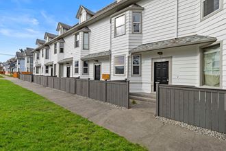 a row of white houses with a sidewalk and grass