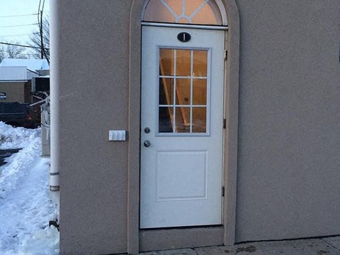 A white door with a glass window is set in a beige wall.