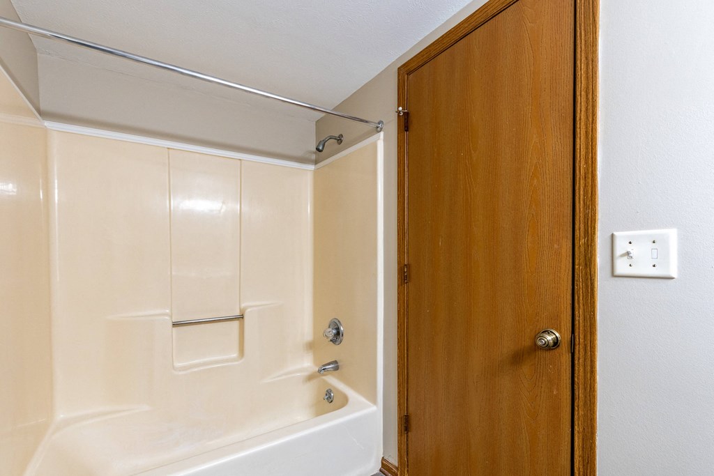 a bathroom with a white tub and a wooden door
