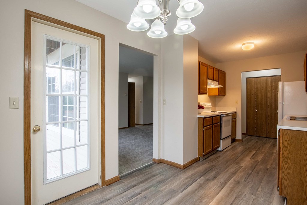 a view of a kitchen and a living room with a door to a hallway