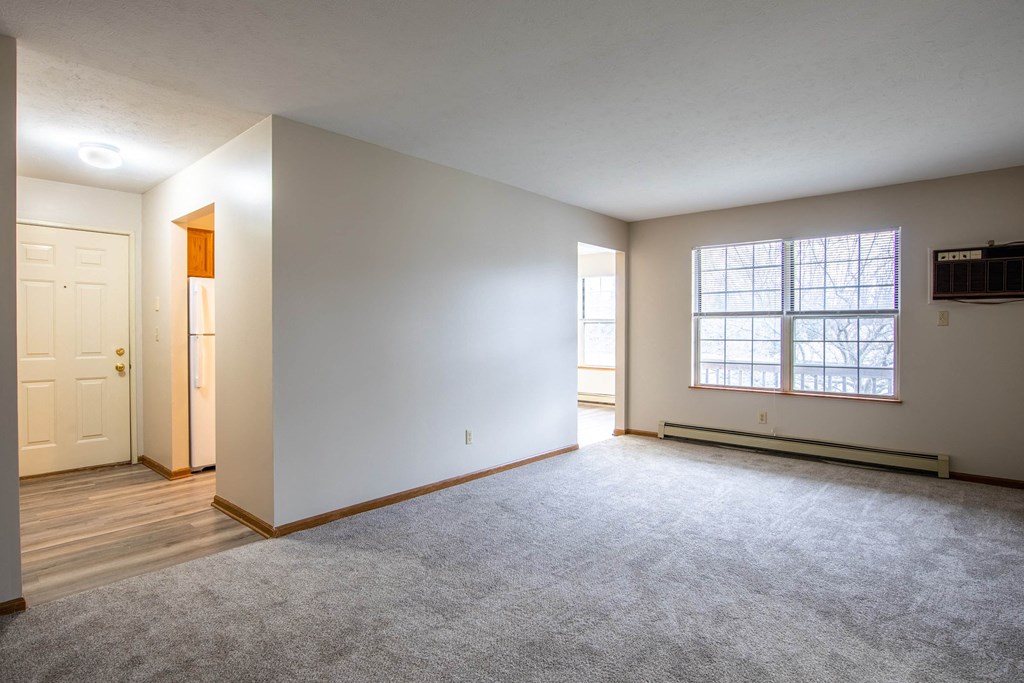 the living room and dining room of an empty home with white walls and wood floors