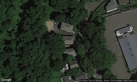 A satellite image shows a parking lot and a building surrounded by trees.