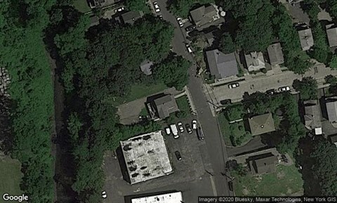 A satellite image shows a residential area with houses and a large parking lot.