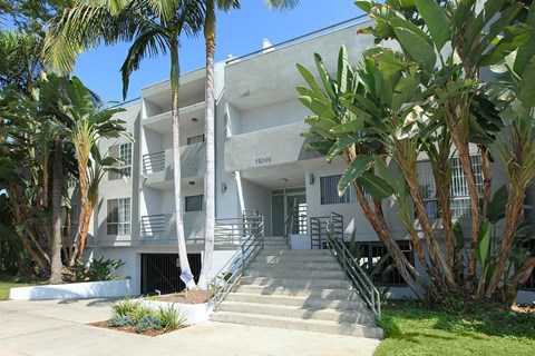 A white building with a black gate and steps leading up to it.