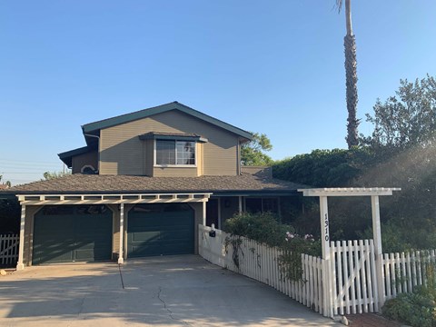 a house with a white fence and a car garage