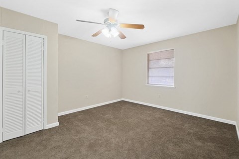 an empty bedroom with a ceiling fan and a closet