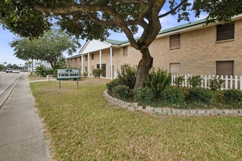 a building with a street sign in front of a tree
