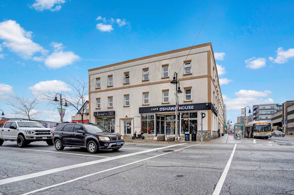 a building on the corner of a city street with cars and a bus