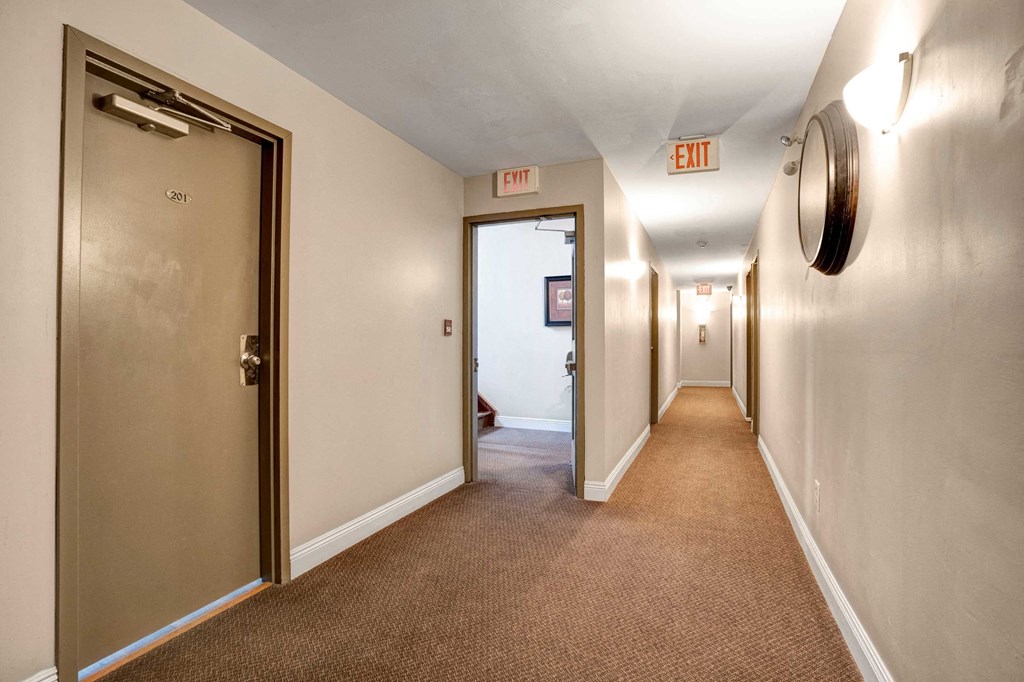 a hallway with an exit sign and a door to a room