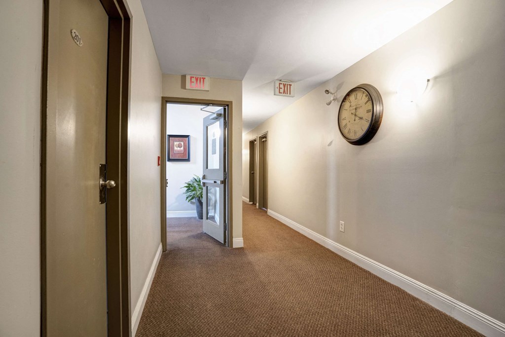 a hallway with a clock on the wall and an open door