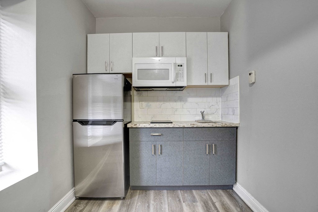 a small kitchen with white cabinets and a stainless steel refrigerator
