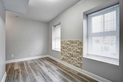 an empty living room with a stone fireplace and wood floors