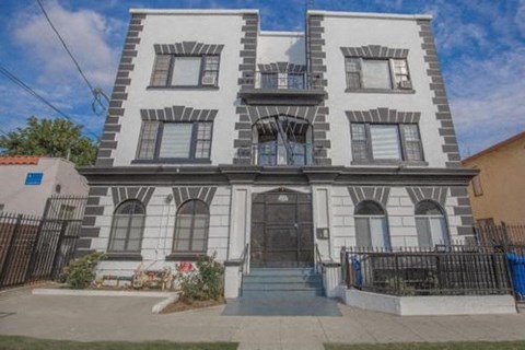 the front of a white house with a black door