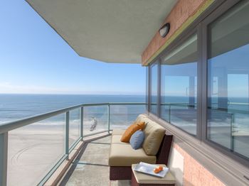 A balcony with a couch and a tray of food overlooking the beach at 10 West Apartments, Long Beach, New York
