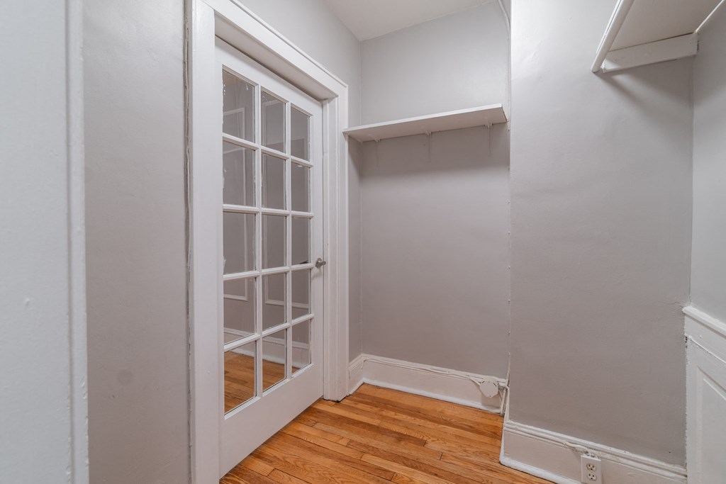 a bedroom with a door to a closet and a wooden floor