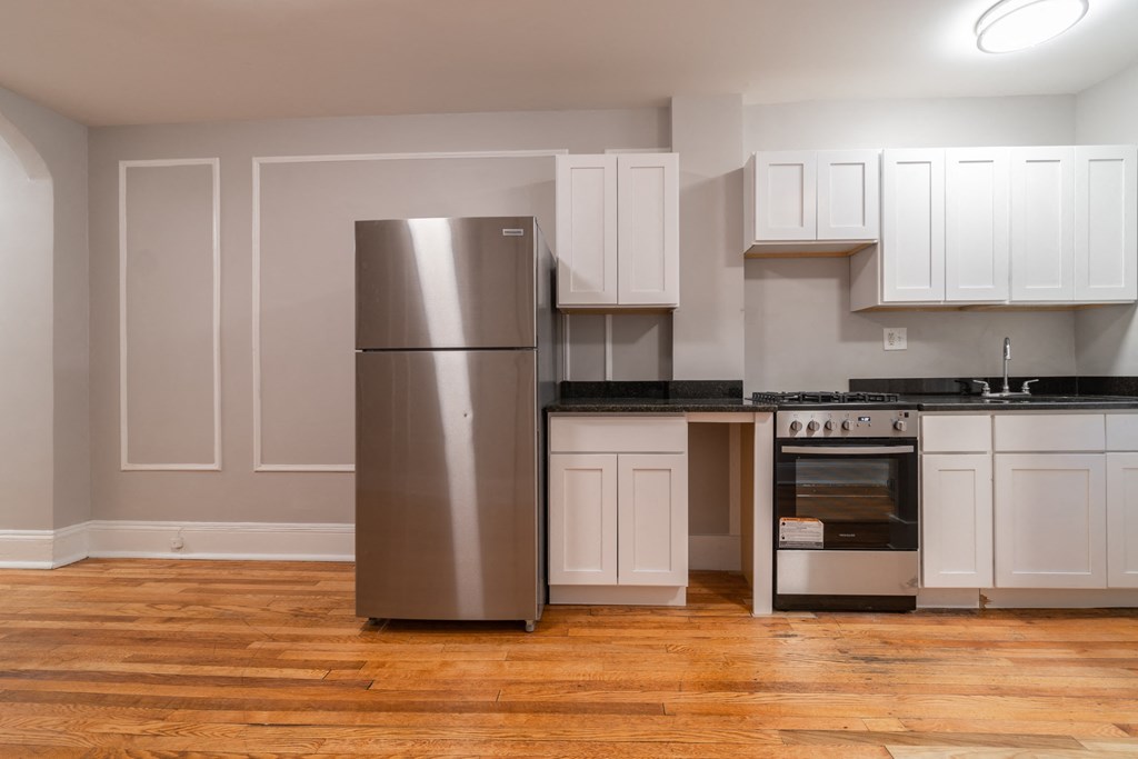 a kitchen with white cabinets and stainless steel refrigerator