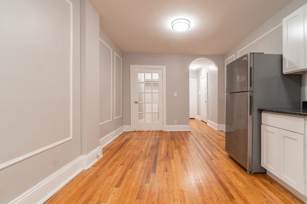 an empty kitchen and living room with wood floors and a refrigerator
