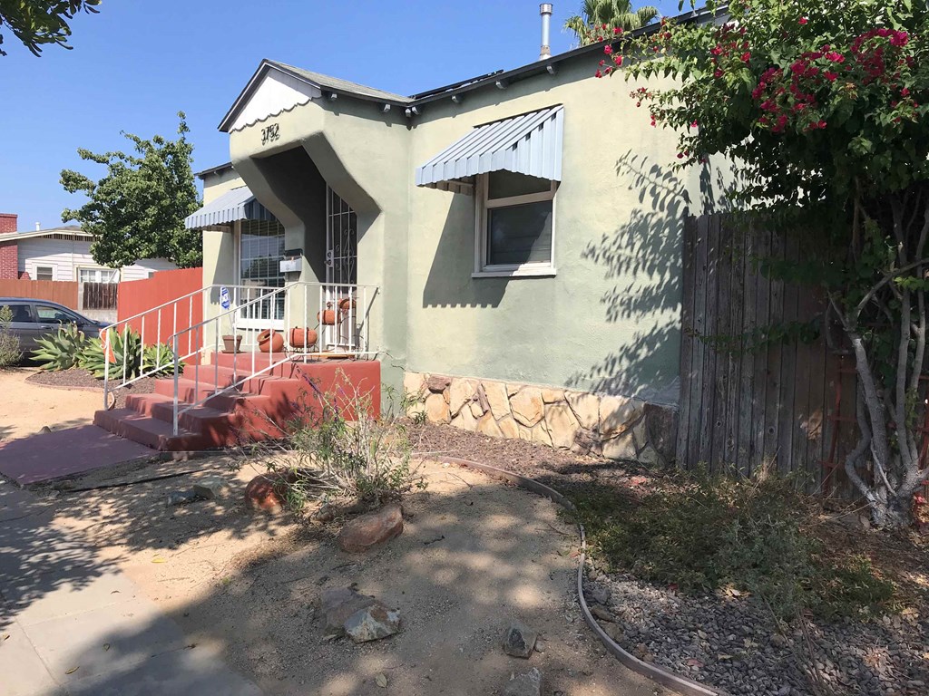 the front of a house with a sidewalk and a fence