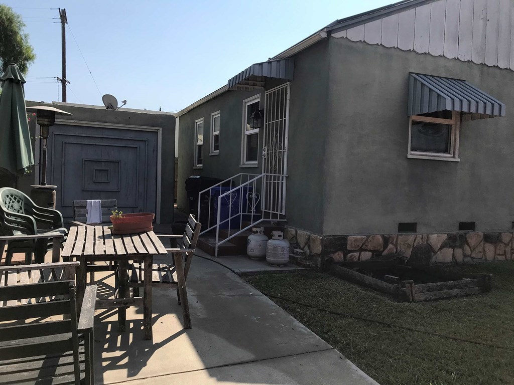 an exterior view of a small gray house with a table and chairs