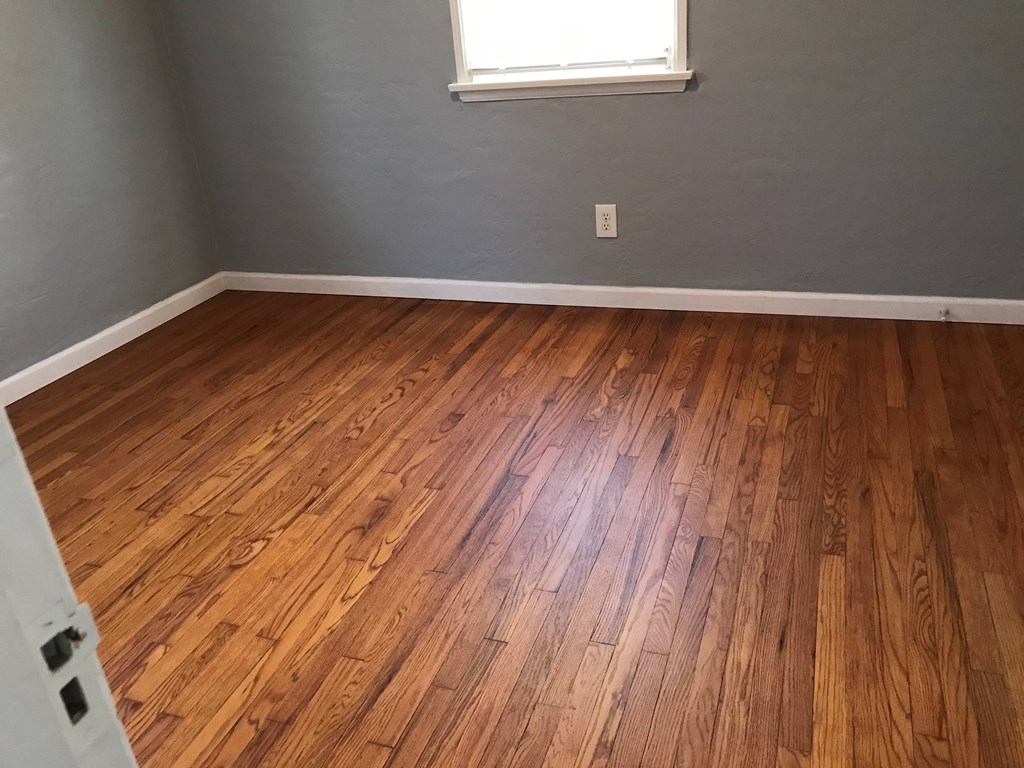 an empty room with wooden floors and a window