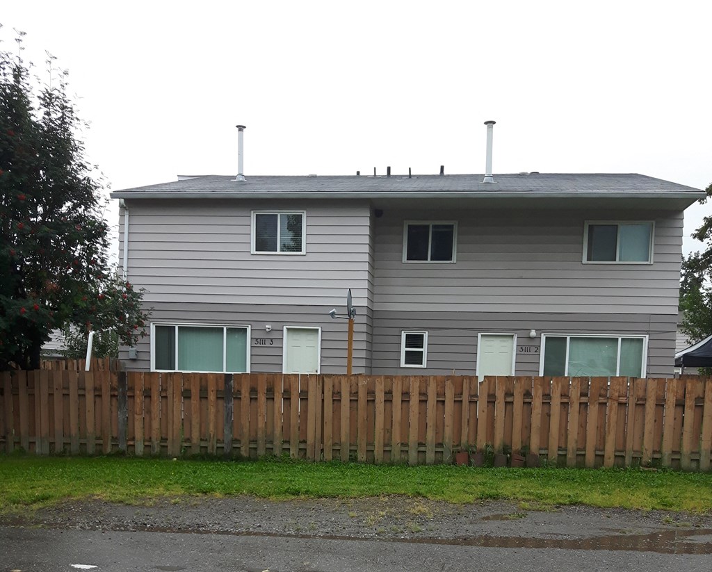 the back of a house with a wooden fence