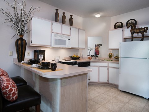 a kitchen with white cabinets and a counter top and a refrigerator
