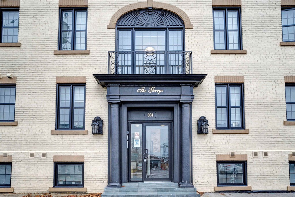 a white brick building with a black door and a balcony
