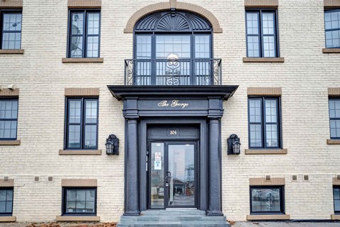 a white brick building with a black door and a balcony