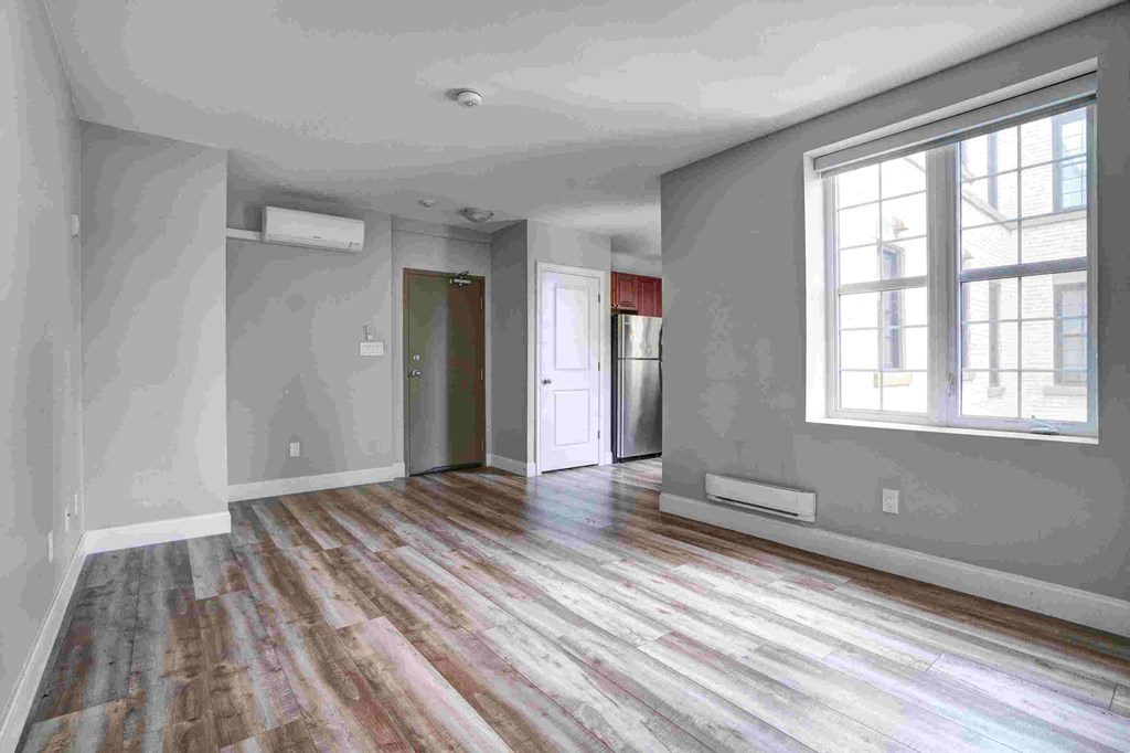an empty living room with grey walls and a large window