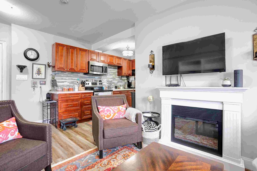 a living room with a fireplace and a kitchen in the background