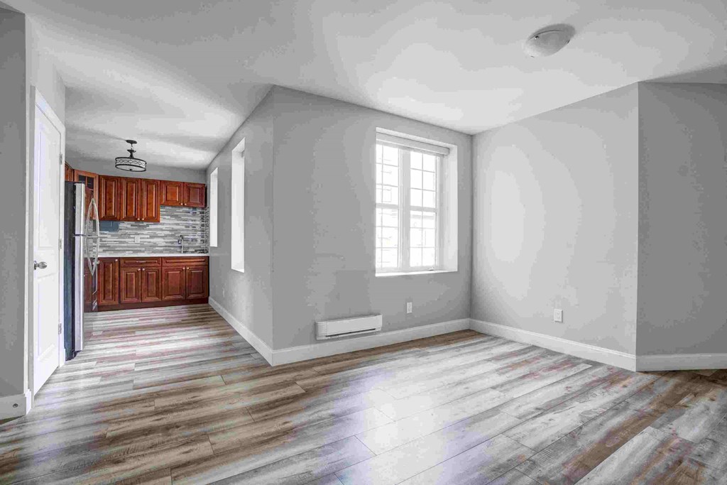 an empty living room with gray walls and wooden floors