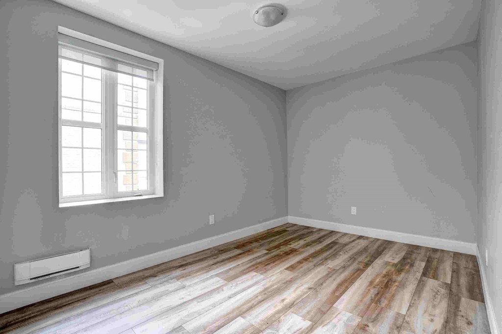 an empty room with wooden floors and a window