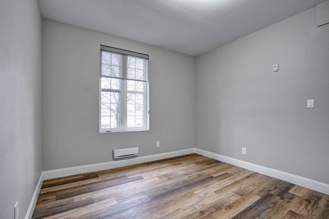 the master bedroom has a large window and hardwood floors