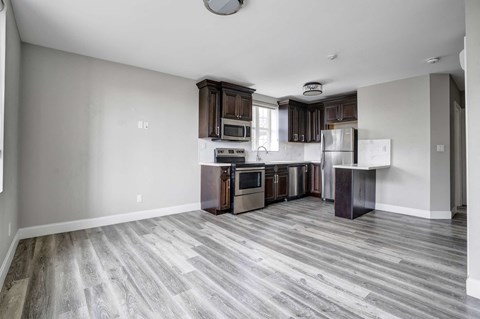 a brand new kitchen with wood flooring and stainless steel appliances
