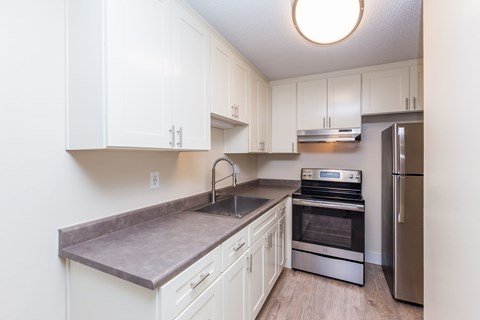 A kitchen with white cabinets and a refrigerator.